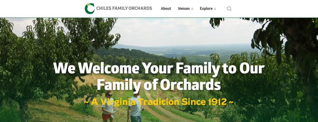 Two people walking in a mountaintop orchard, with a text overlay which says "We Welcome Your Family to Our Family of Orchards -A Virginia Tradition Since 1912"