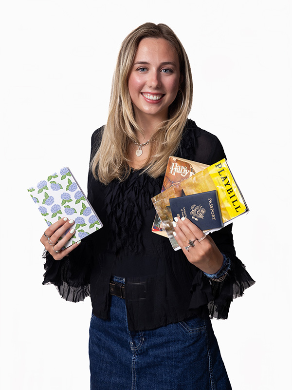 A woman holding a passport and other small objects.